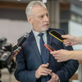 Grey-haired bearded man looking unsatisfied at the press conference